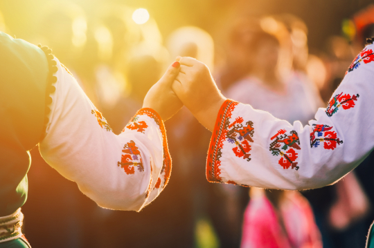 Zwei Frauen in traditioneller Tracht von hinten, die sich an der Hand halten